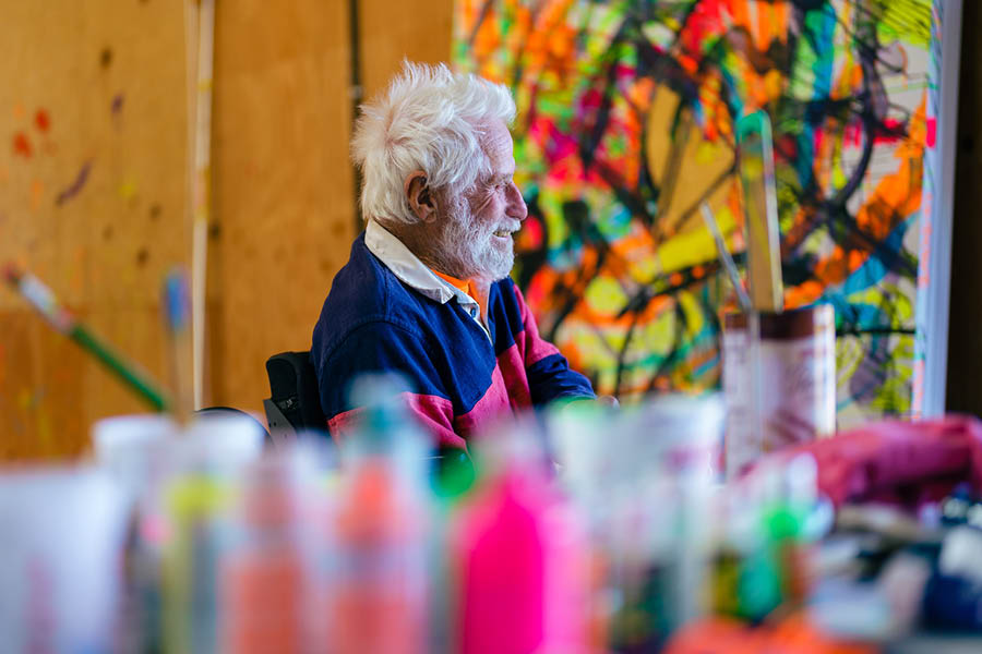 Artist ark di Suvero sitting in his studio with colorful paints in foreground