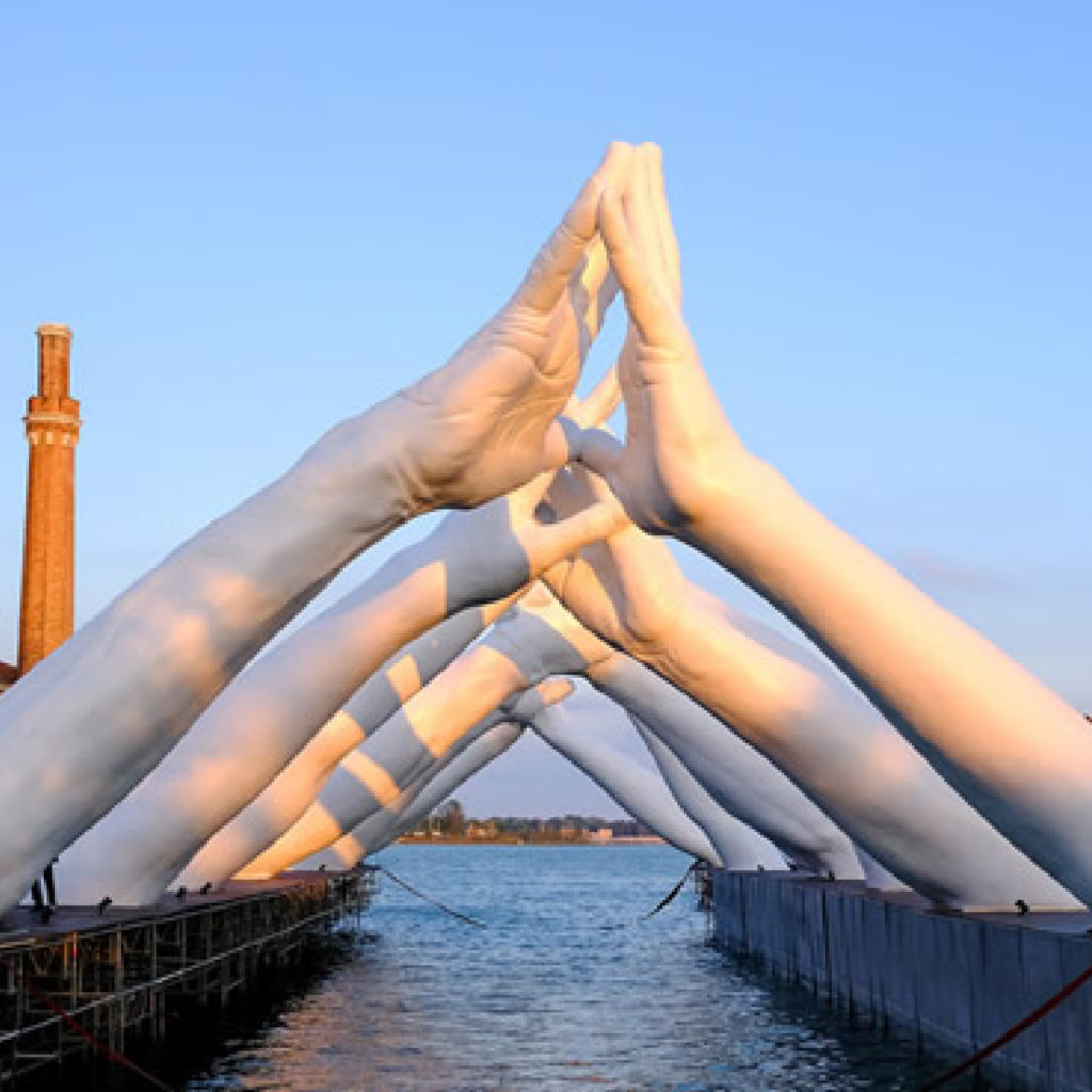 "Building Bridges" from the Venice biennale. Artist: Lorenzo-Quinn. Large sculptural installation of white arms extending out from the water to create a tunnel