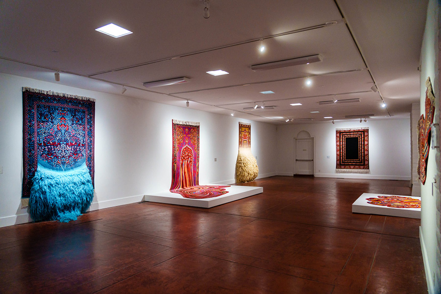 Gallery view of "Faig Ahmed: Collision." Colorful tapestries seemingly melt onto the floor