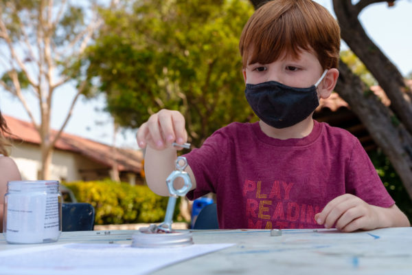 A young boy in a mask works on an art project at SLOMA's Second Saturdays event