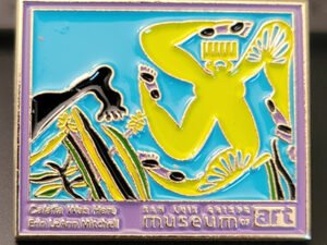 Enamel pin featuring the dancing figure from "Calafia was Here." A lime green figure comprised of four rotating legs and a duafe for a head, over a bright blue background.