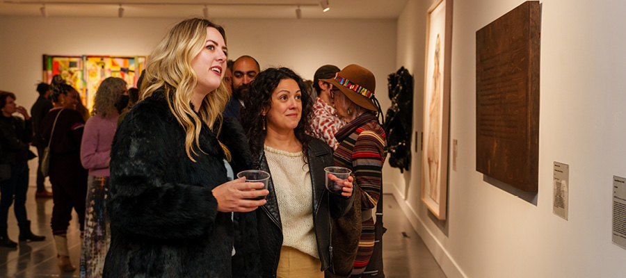 A pair of young women look at artwork in a gallery