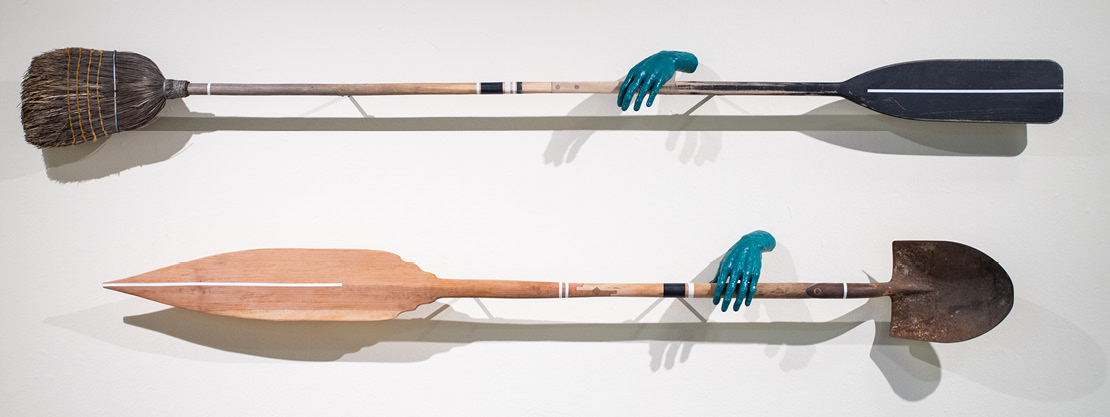 Blue hands hold tools of agriculture and water navigation on a wall