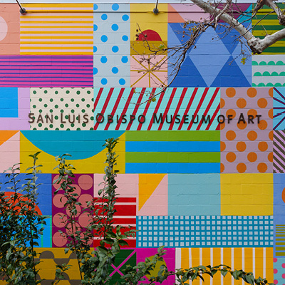 Detail of "SLO(W) Rainbow" by Leah Rosenberg, SLOMA's 2023 mural project. Closeup of the creekside wall with squares filled with different patterns and colors