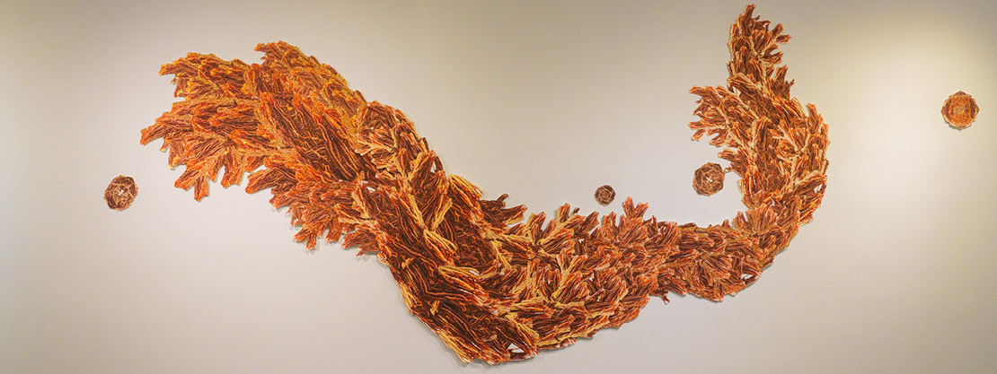 "Sunbird" artwork consisting of layers of photos of vibrant orange and yellow braided locks of hair
