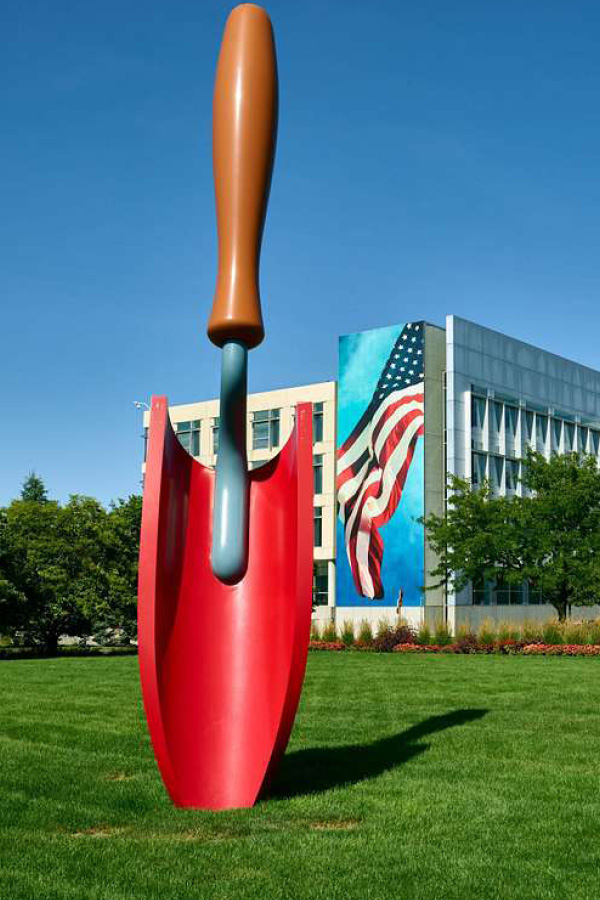 A larger than life sculpture of a red trowel sticking in the ground