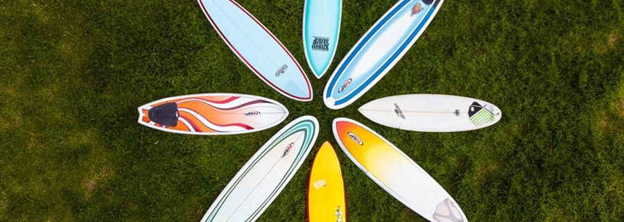 8 surfboards arranged in a flower pattern, on a lawn