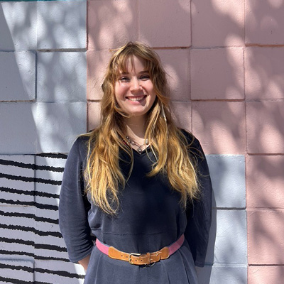 Photo of a young woman in front of a colorfully painted wall