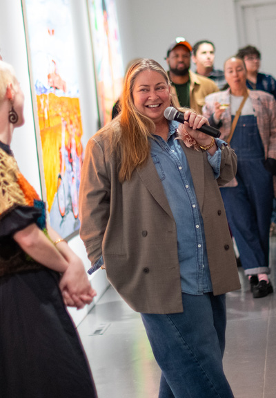 SLOMA Executive Director Leann Standish A blonde woman holding a microphone, smiling