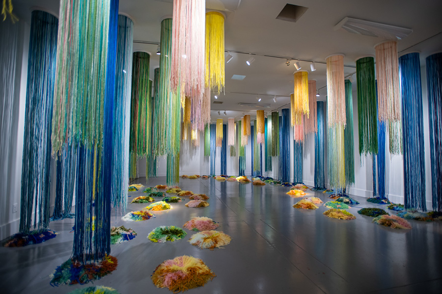 A museum gallery with hanging textiles in bright colors