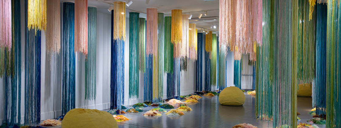 Trish Andersen: Little by Little installation A museum gallery with hanging textiles in bright colors