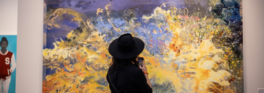 Woman wearing a hat looking at a piece of art