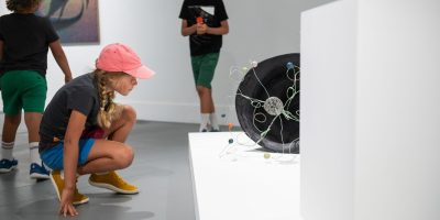 Curriculum Guide A child wearing a pink hat kneals to look at an artwork more closely