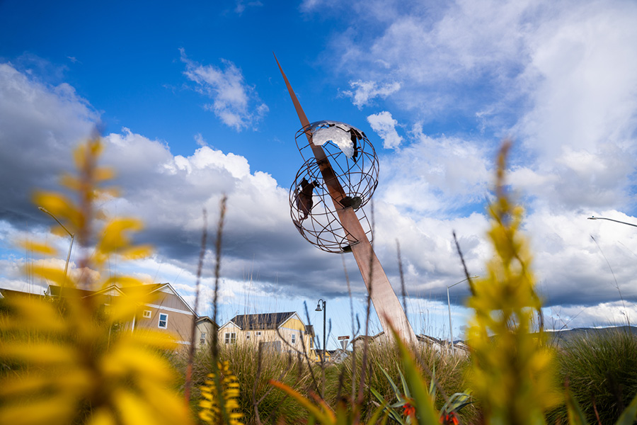 A tall metal sculpture depicting a skyward shard bisecting a globe